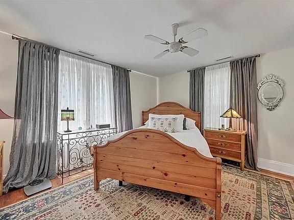 bedroom with baseboards, ceiling fan, wood finished floors, and visible vents