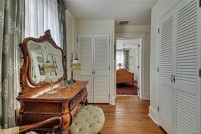 corridor featuring baseboards, plenty of natural light, wood finished floors, and visible vents
