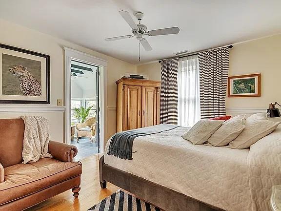bedroom with multiple windows, a ceiling fan, wood finished floors, and access to exterior