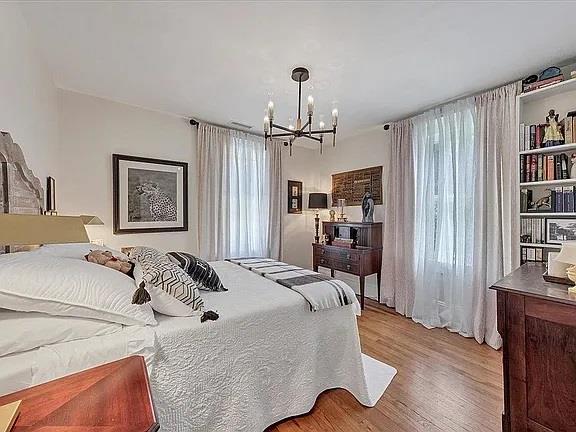 bedroom with a chandelier, multiple windows, and wood finished floors