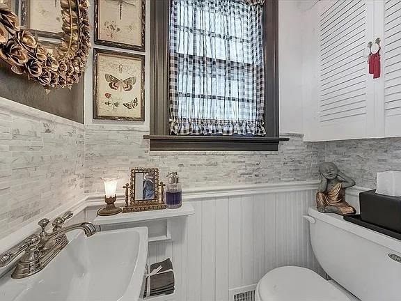 bathroom with visible vents, a sink, a wainscoted wall, and toilet