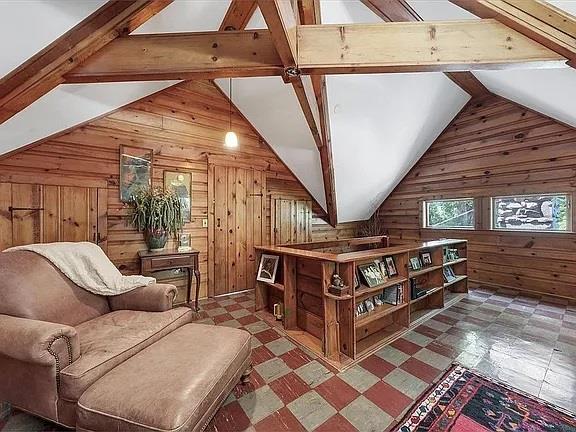 sitting room featuring wooden walls, tile patterned floors, and lofted ceiling with beams