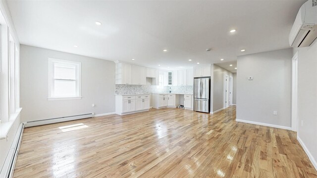 13108 160th St, Jamaica, NY 11434 - unfurnished living room featuring a baseboard radiator, a wall unit AC, light wood-style floors, baseboard heating, and recessed lighting