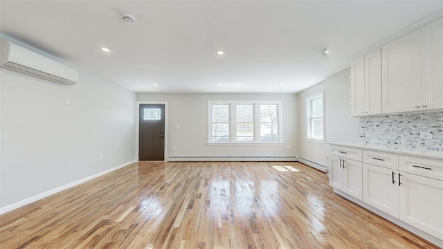 13108 160th St, Jamaica, NY 11434 - unfurnished living room with an AC wall unit, light wood-style floors, recessed lighting, baseboards, and a baseboard radiator