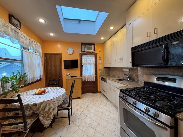 kitchen with white cabinets, black microwave, a sink, gas stove, and a skylight