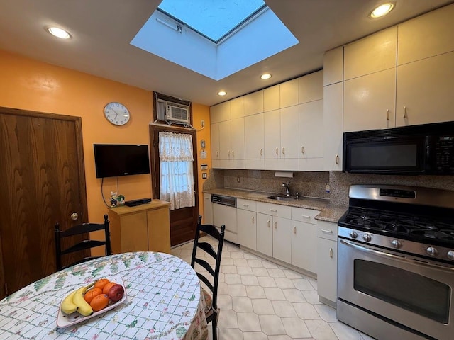 kitchen with stainless steel gas range, white dishwasher, black microwave, a sink, and a skylight