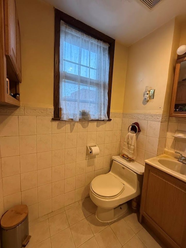 bathroom featuring tile walls, tile patterned flooring, a wainscoted wall, vanity, and toilet