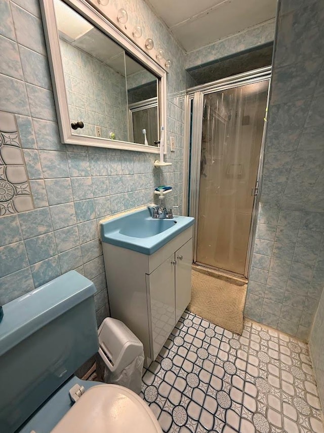 full bath with vanity, toilet, tile walls, and a stall shower