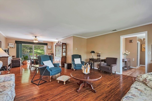living room with visible vents, ornamental molding, wood finished floors, baseboards, and ceiling fan