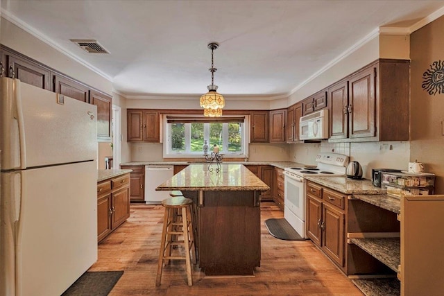 kitchen with white appliances, a breakfast bar area, a center island, and light wood-style floors