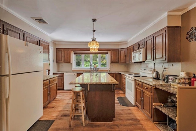 kitchen with a breakfast bar, a kitchen island, white appliances, and light wood-style flooring