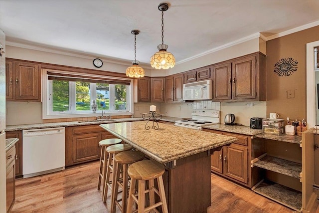 kitchen featuring light wood-style floors, a sink, a kitchen island, and white appliances