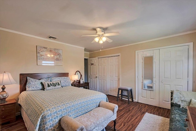 bedroom featuring a ceiling fan, dark wood-style flooring, visible vents, crown molding, and two closets