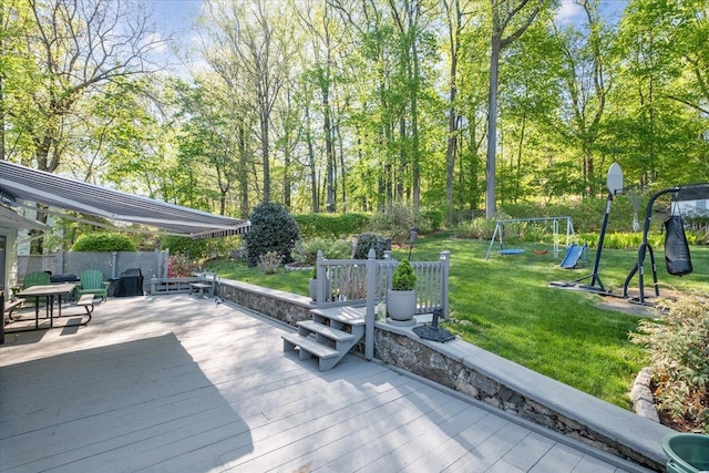 wooden deck with a lawn, a playground, and fence