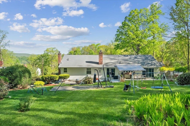 back of house featuring a yard, a patio, and a chimney