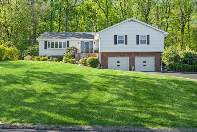split level home with an attached garage, a front lawn, driveway, and brick siding