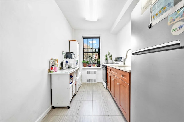 interior space featuring black stove, baseboards, freestanding refrigerator, radiator, and light tile patterned flooring