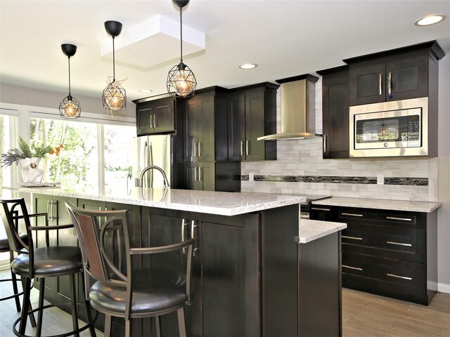 256 Macy Rd, Briarcliff Manor, NY 10510 - kitchen with a kitchen island with sink, tasteful backsplash, stainless steel appliances, recessed lighting, and wall chimney exhaust hood