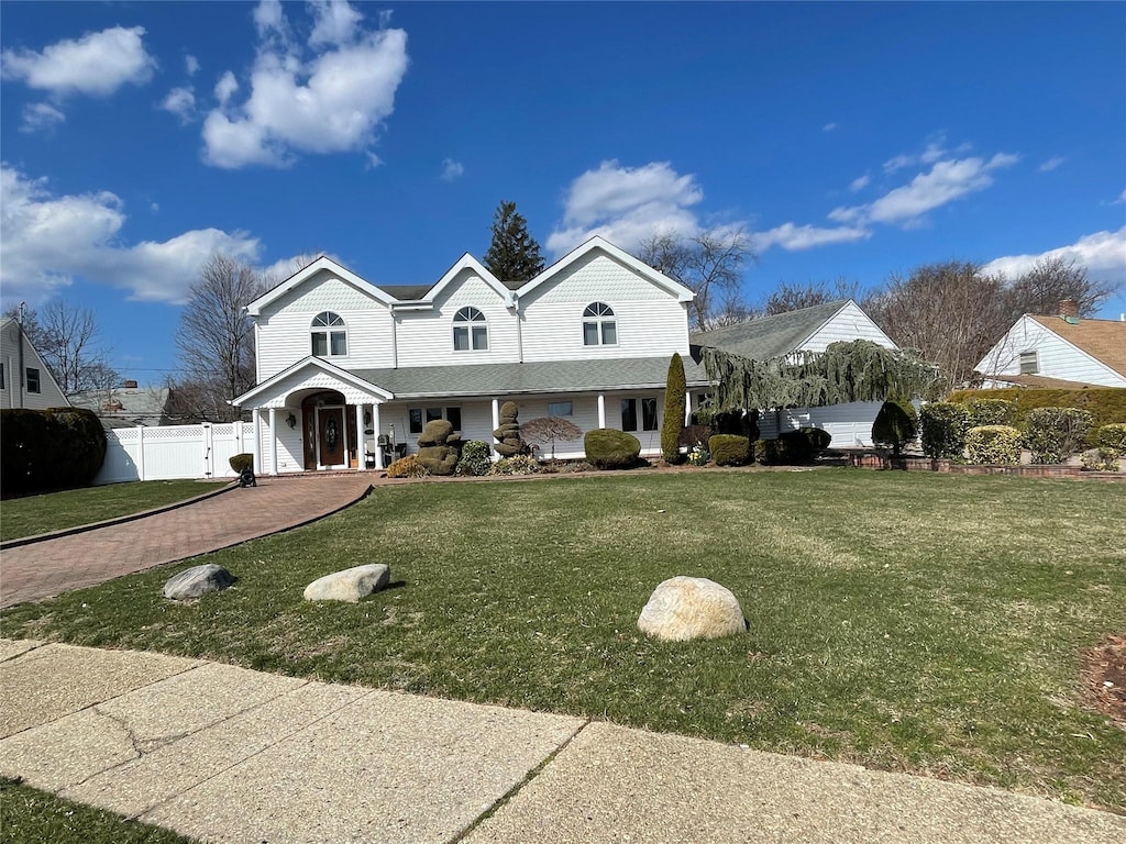 view of front of house featuring a front lawn, fence, and covered porch