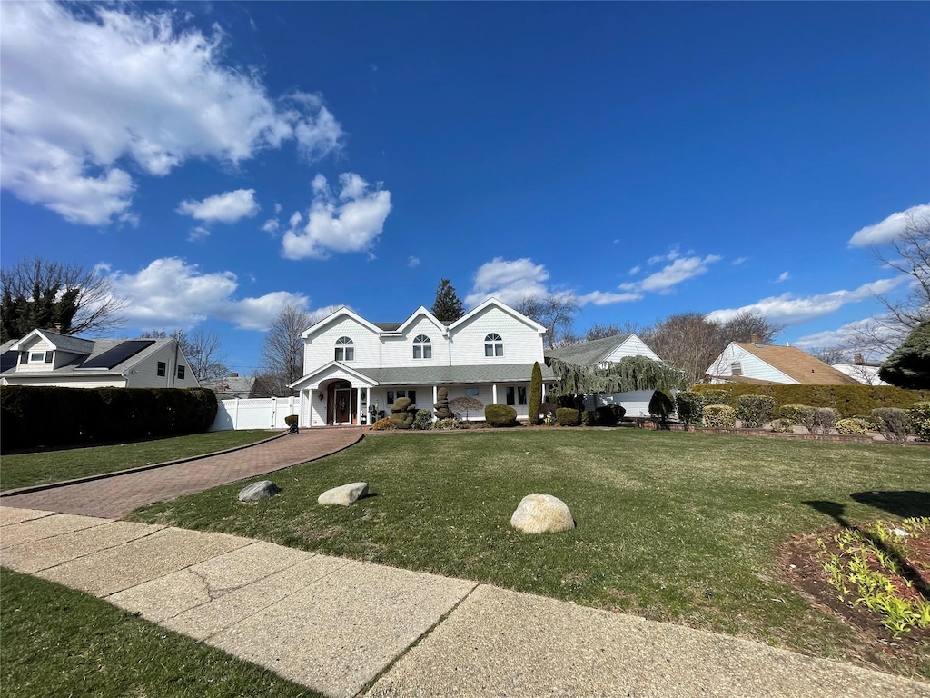 view of front of property with a porch, decorative driveway, a front lawn, and fence