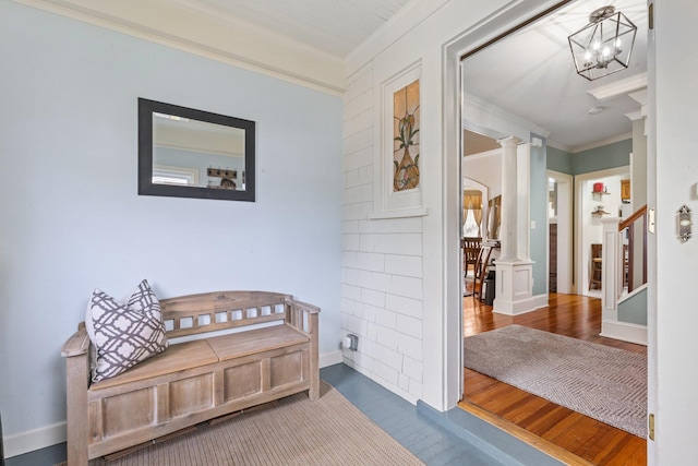 hall featuring crown molding, wood finished floors, stairway, a notable chandelier, and ornate columns