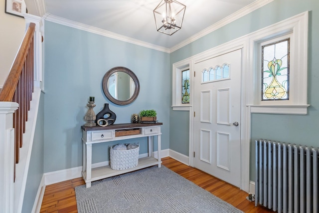 foyer with crown molding, a chandelier, radiator heating unit, baseboards, and wood finished floors