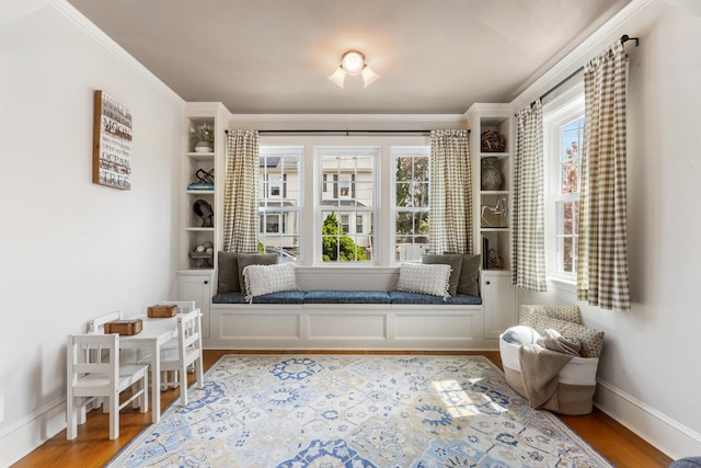 sitting room with baseboards, light wood finished floors, and crown molding