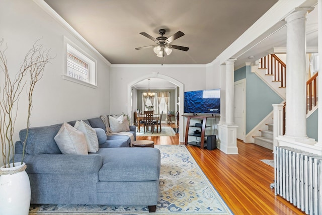 living area featuring ornamental molding, radiator heating unit, stairway, light wood-style flooring, and ceiling fan with notable chandelier