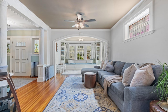 living room featuring ceiling fan, plenty of natural light, ornate columns, and wood finished floors