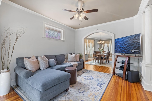 living room with arched walkways, ornamental molding, wood finished floors, and ceiling fan with notable chandelier