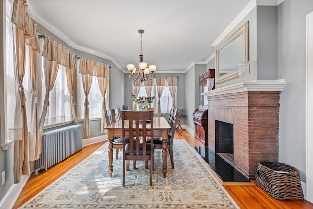 dining area featuring radiator heating unit, ornamental molding, light wood finished floors, and a notable chandelier