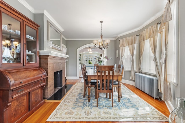 dining room with radiator heating unit, arched walkways, an inviting chandelier, and ornamental molding