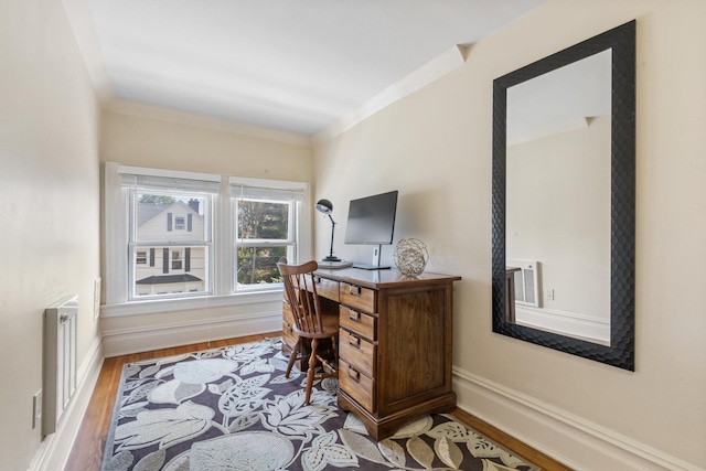 office space with baseboards, ornamental molding, wood finished floors, and radiator