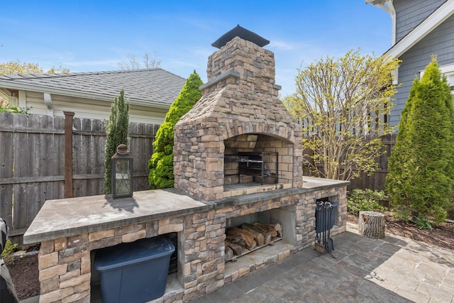 view of patio featuring an outdoor stone fireplace and fence