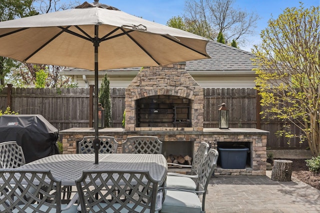 view of patio / terrace featuring grilling area, an outdoor stone fireplace, fence, and outdoor dining space