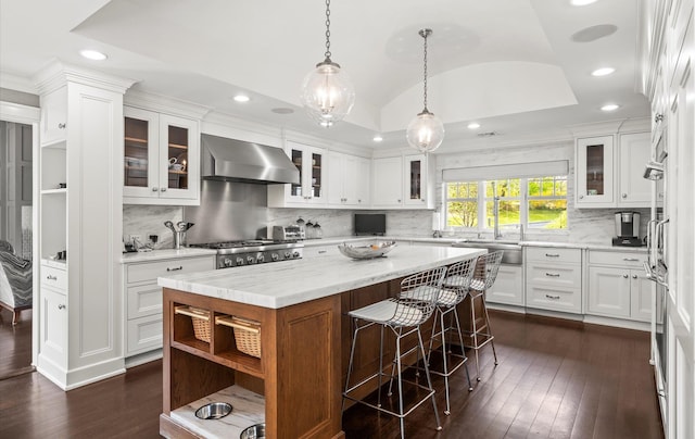kitchen featuring wall chimney range hood, dark wood-style flooring, a center island, white cabinets, and recessed lighting