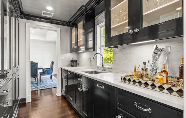 kitchen with dark cabinets, a sink, crown molding, and visible vents