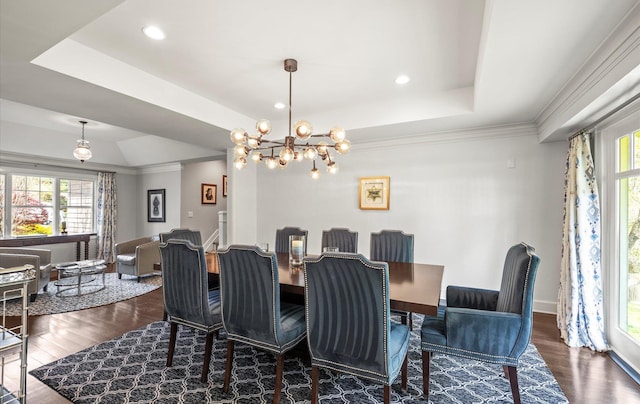 dining space with a tray ceiling, dark wood-type flooring, a chandelier, and a wealth of natural light