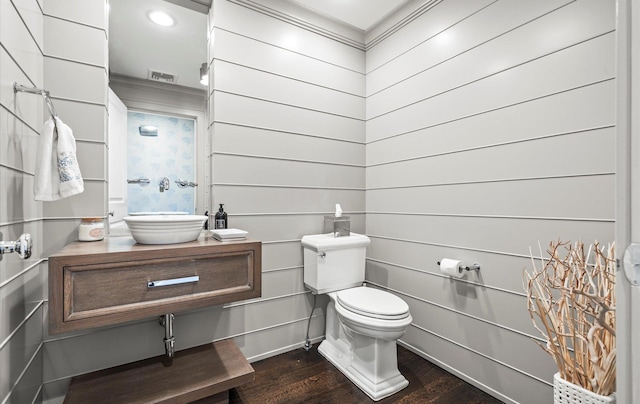 half bathroom featuring vanity, ornamental molding, wood finished floors, and toilet