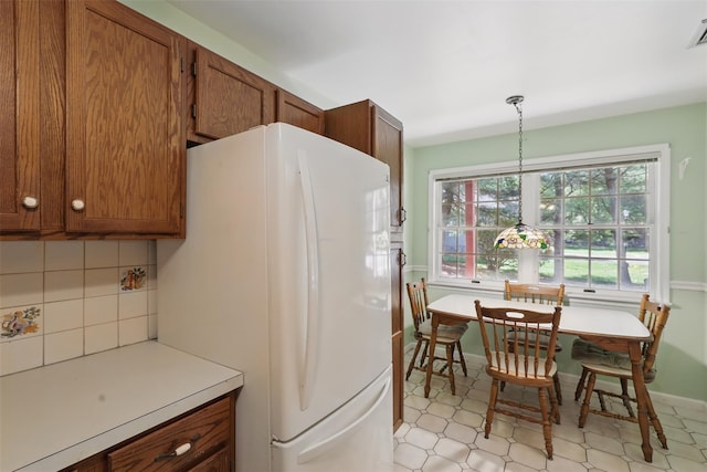 21 Lamplight St, Beacon, NY 12508 - kitchen with brown cabinets, light countertops, freestanding refrigerator, backsplash, and visible vents