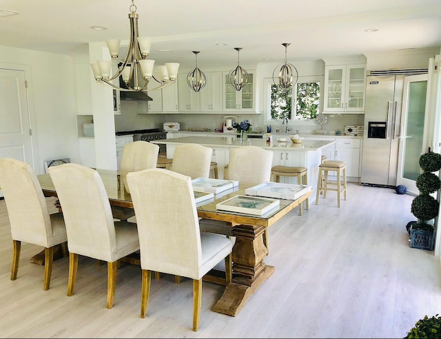 dining room featuring light wood-type flooring, recessed lighting, and a notable chandelier