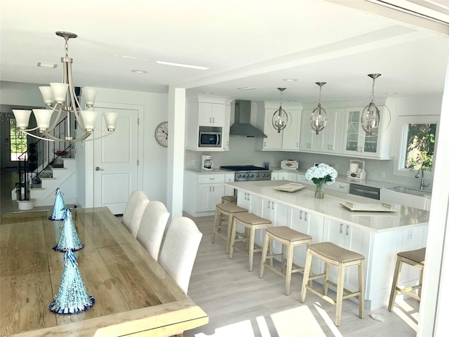 dining area featuring an inviting chandelier, light wood-style floors, and stairs