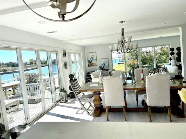 dining room featuring a notable chandelier, recessed lighting, wood finished floors, a water view, and visible vents