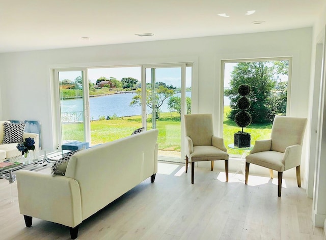 interior space with a water view, light wood-style flooring, and visible vents
