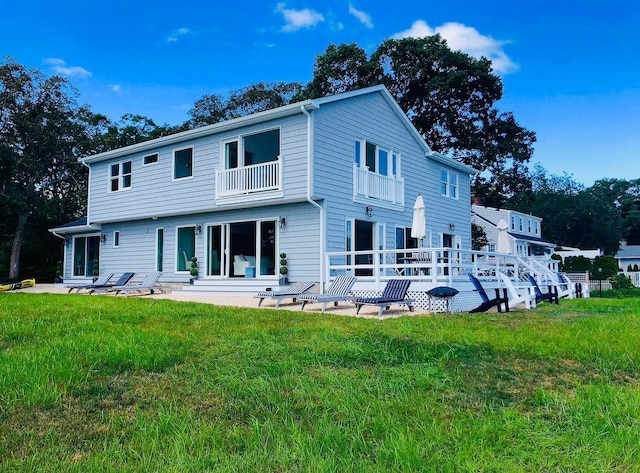 back of property with a patio, a yard, and a balcony
