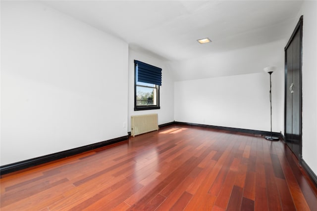 bonus room featuring wood finished floors, baseboards, radiator, and lofted ceiling
