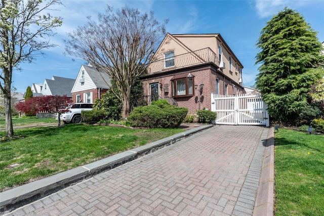 view of front facade with brick siding, a front lawn, a gate, and a balcony
