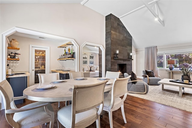 2307 Hawthorne Dr, Yorktown Heights, NY 10598 - dining area featuring a tile fireplace, hardwood / wood-style flooring, bar area, and high vaulted ceiling