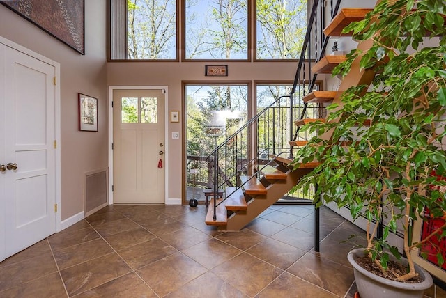 entrance foyer featuring baseboards, a towering ceiling, stairway, and dark tile patterned flooring