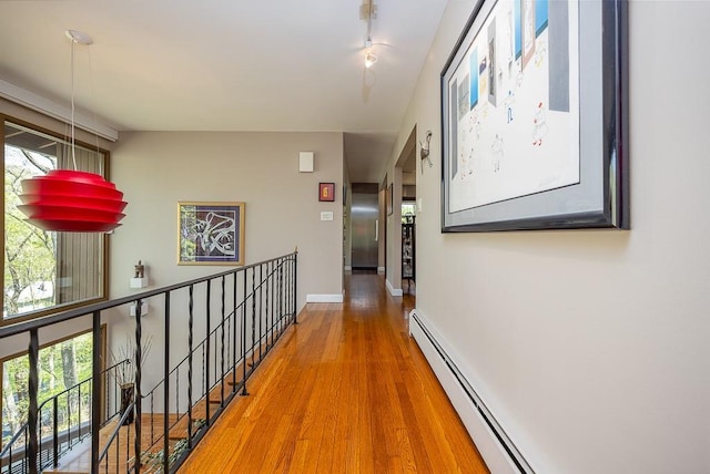hallway with baseboards, a baseboard heating unit, and wood finished floors
